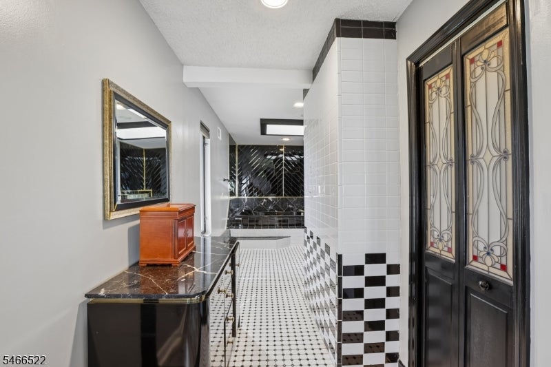 Entry hallway with black-and-white tile, a marble-topped console, and stained-glass double doors.