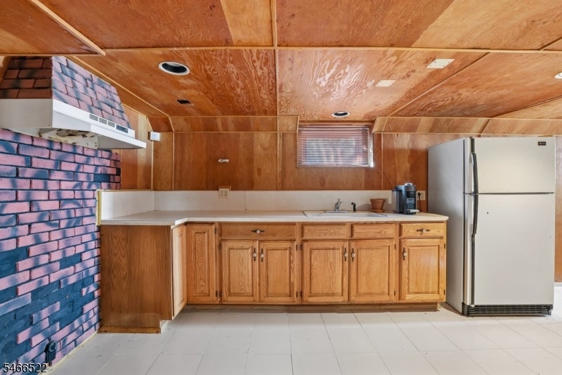 Kitchen with wood cabinets, white countertops, and a blue-and-pink brick accent wall.