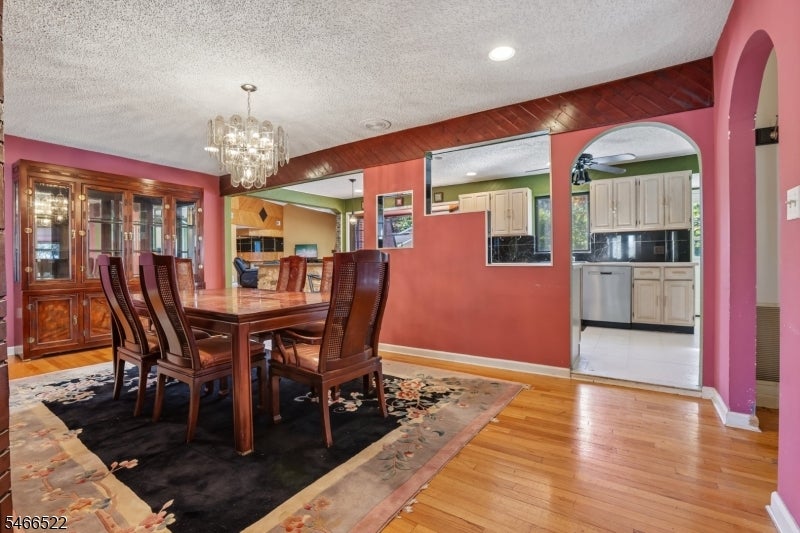 Dining room with a dark wood table, glass-front china cabinet, chandelier, and hardwood floors.