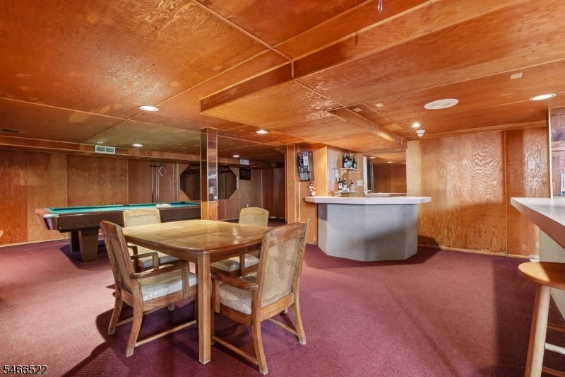 Basement recreation room with a pool table, dining table, and curved-front bar.