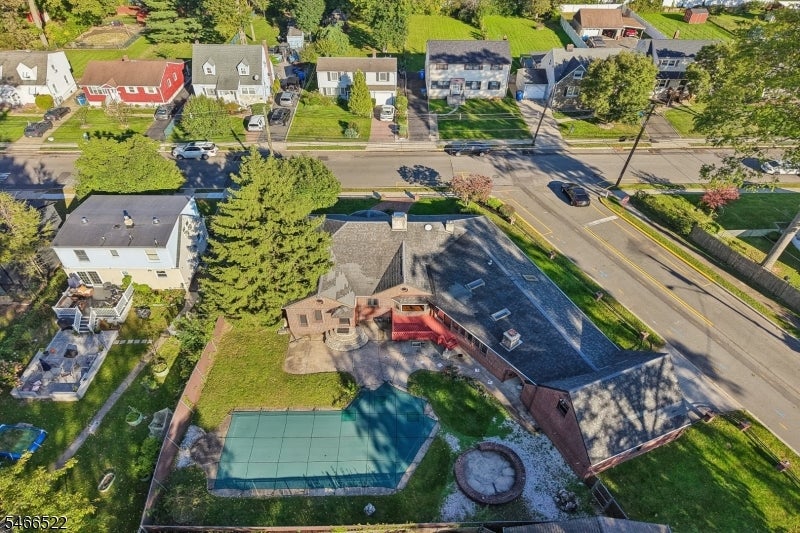 Aerial view of a brick house with a fenced backyard court and surrounding homes.