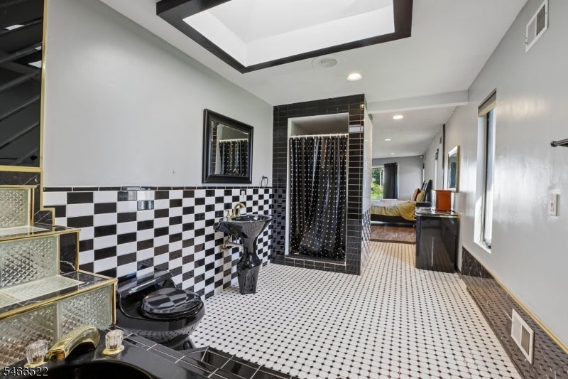 Bathroom with checkerboard tiles, black fixtures, a curtained shower, and glass-block steps.