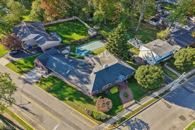 Aerial view of a brick home on a corner lot beside a landscaped yard and swimming pool.