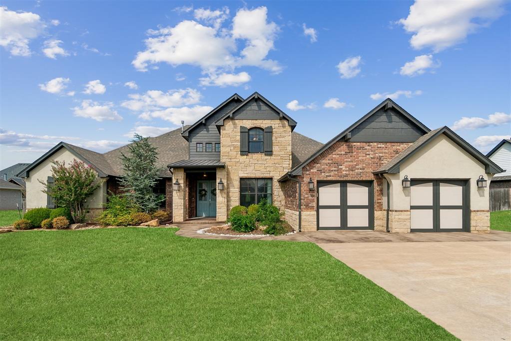 Two-story stone-and-brick house with a three-car garage and broad green lawn.