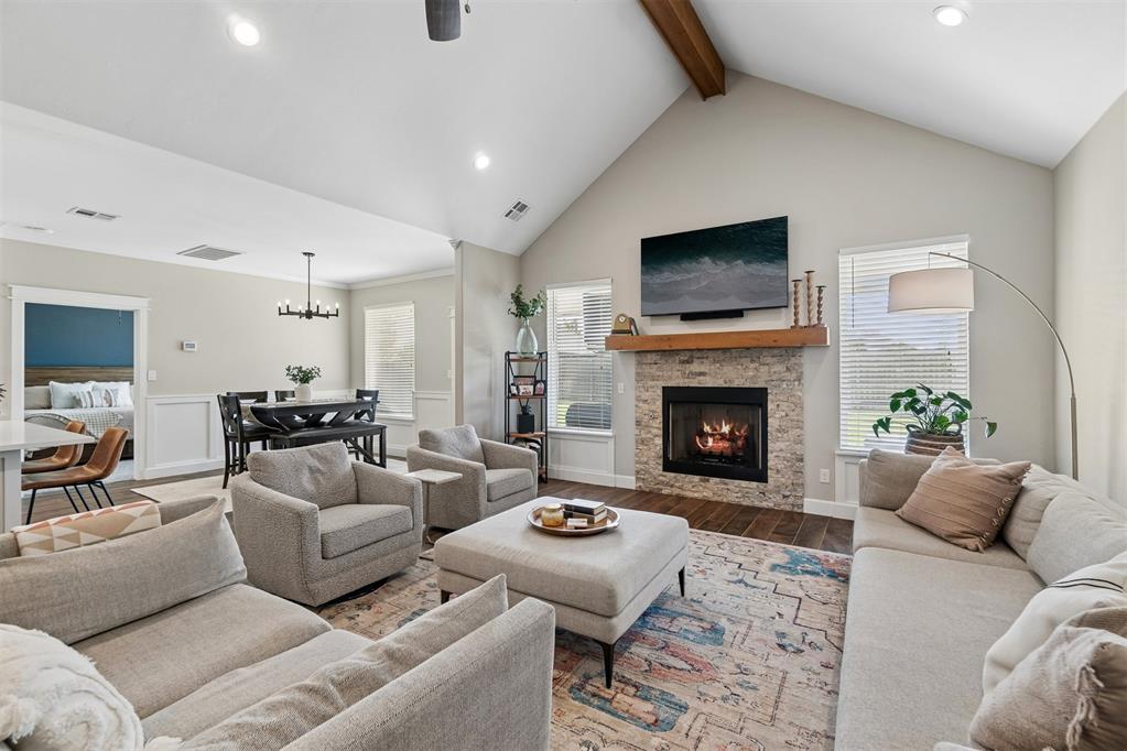Living room with a vaulted ceiling, stone fireplace, and adjoining dining area.