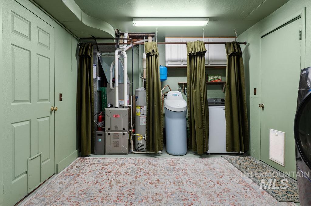 Laundry room with washer and dryer, water softener, furnace, and olive curtains.