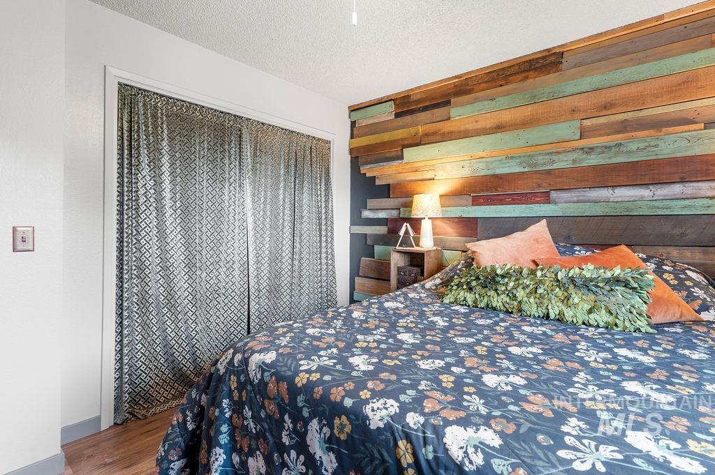 Bedroom with a multicolored reclaimed-wood headboard and dark floral bedding.
