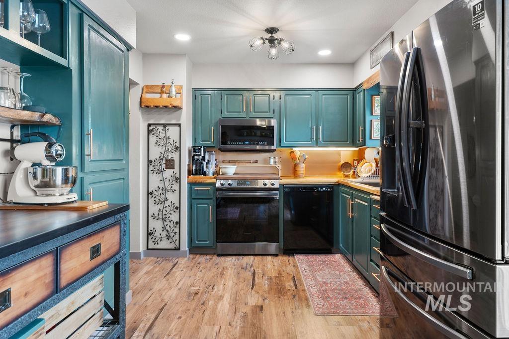 Kitchen with teal cabinets, stainless-steel appliances, and warm under-cabinet lighting.