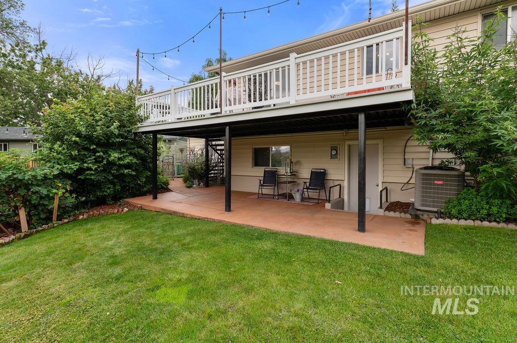 Home’s elevated deck and covered patio with outdoor chairs, overlooking a green lawn.