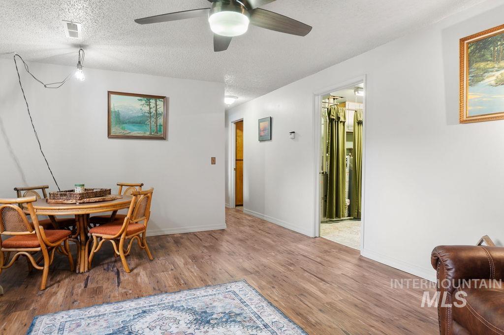 Dining area with a round wicker table, wood-look flooring, and a doorway to a curtained closet.