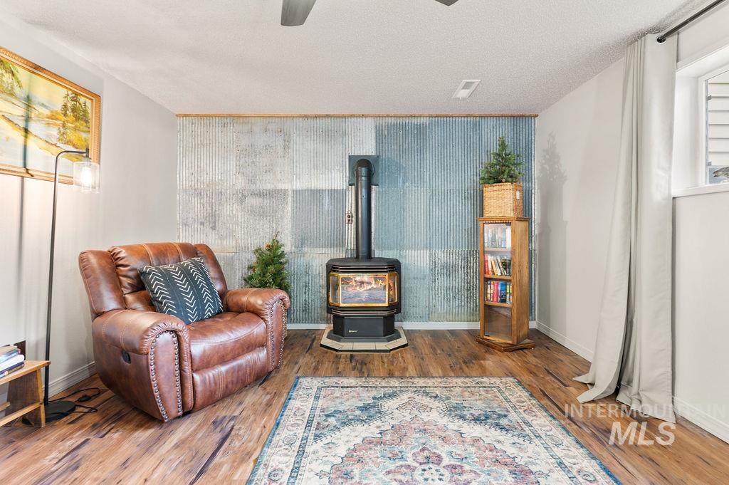 Living room with a black wood stove, corrugated metal accent wall, and brown leather armchair.