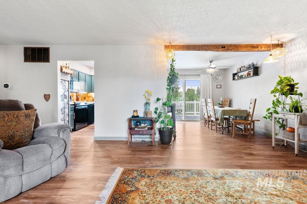 Open living and dining area with hardwood floors, a gray recliner, teal kitchen cabinets, and sliding doors to a deck.