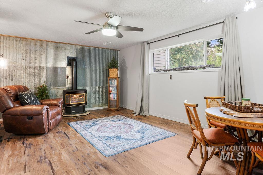 Living room with a wood stove, corrugated metal accent wall, leather recliner, and adjoining dining area.