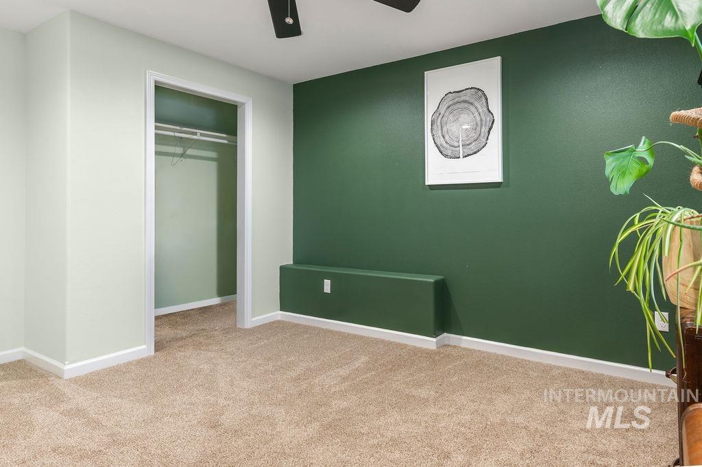 Carpeted room with a dark green accent wall, open closet, and low built-in ledge.