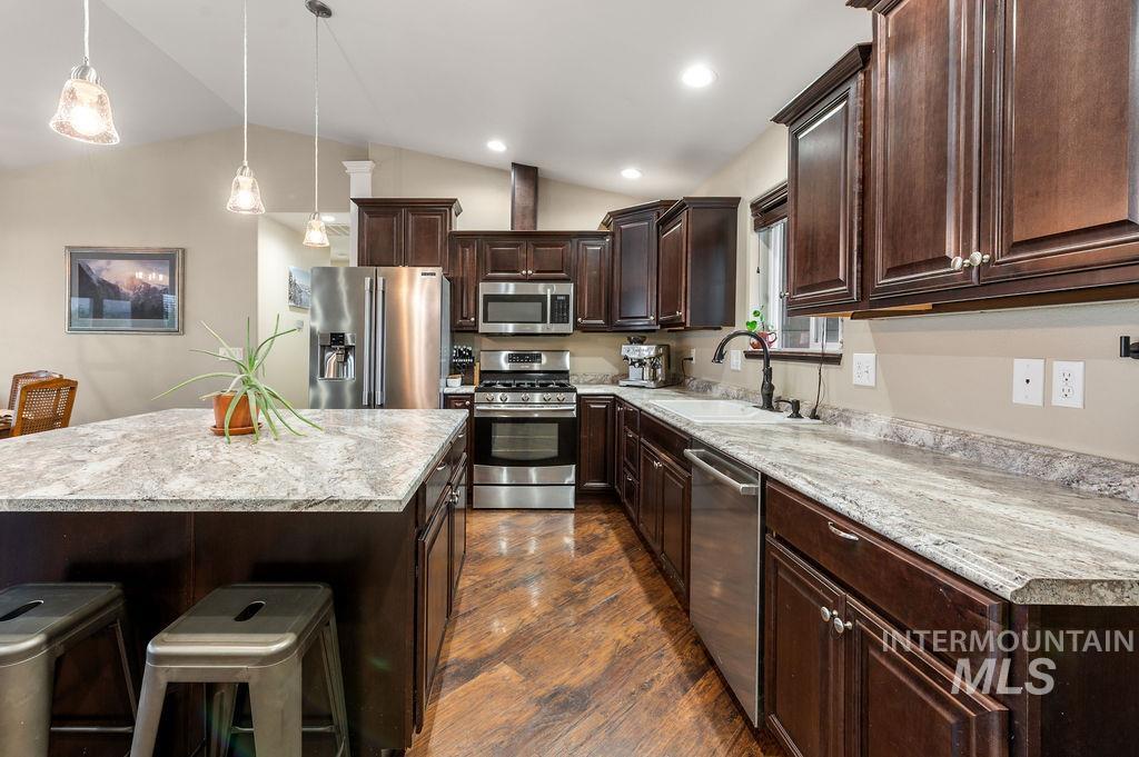 Kitchen with dark wood cabinets, granite countertops, stainless steel appliances, and a large island.