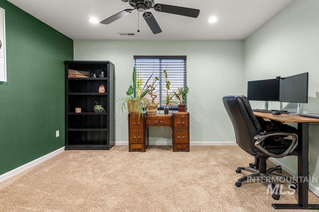 Home office with a green accent wall, wooden desk, potted plants, and computer workstation.