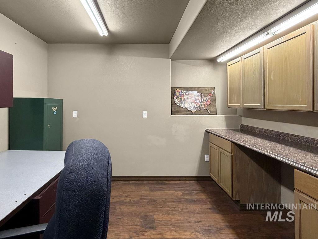 Office with a desk, green storage cabinet, and built-in cabinets along a long countertop.