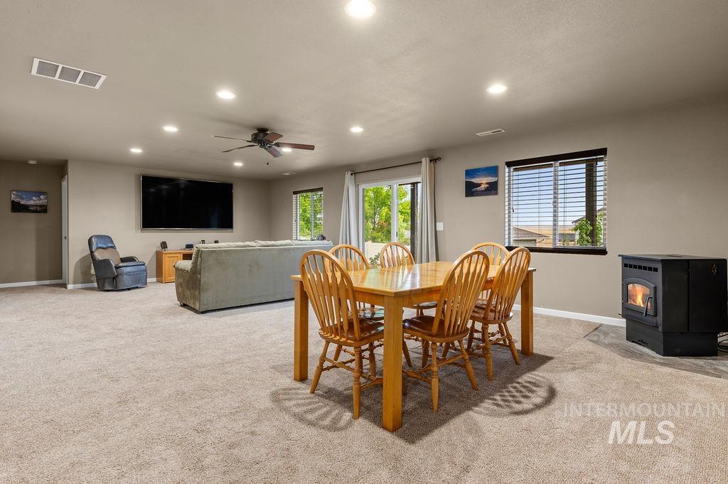 Open living and dining room with a wooden table, gray sofa, and freestanding stove.