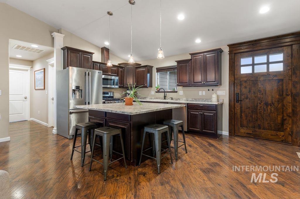 Kitchen with a large island, dark wood cabinets, stainless steel appliances, and a rustic wooden door.