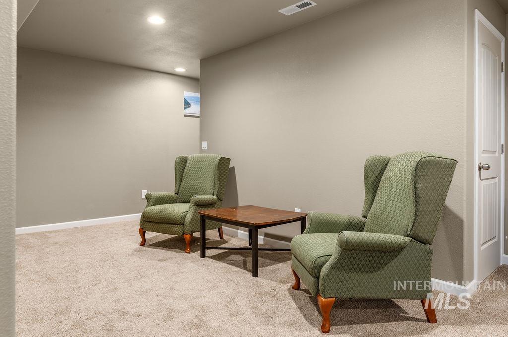 Furnished sitting area with two green armchairs, a wooden coffee table, and beige carpet.