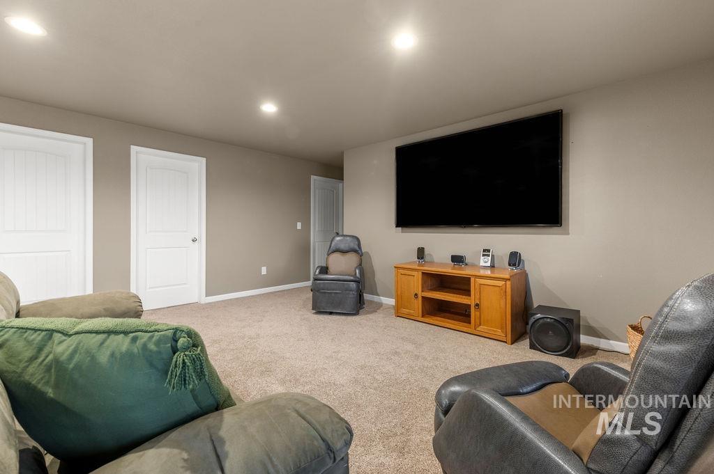 Furnished media room with a wall-mounted television, wooden console, and reclining chairs.