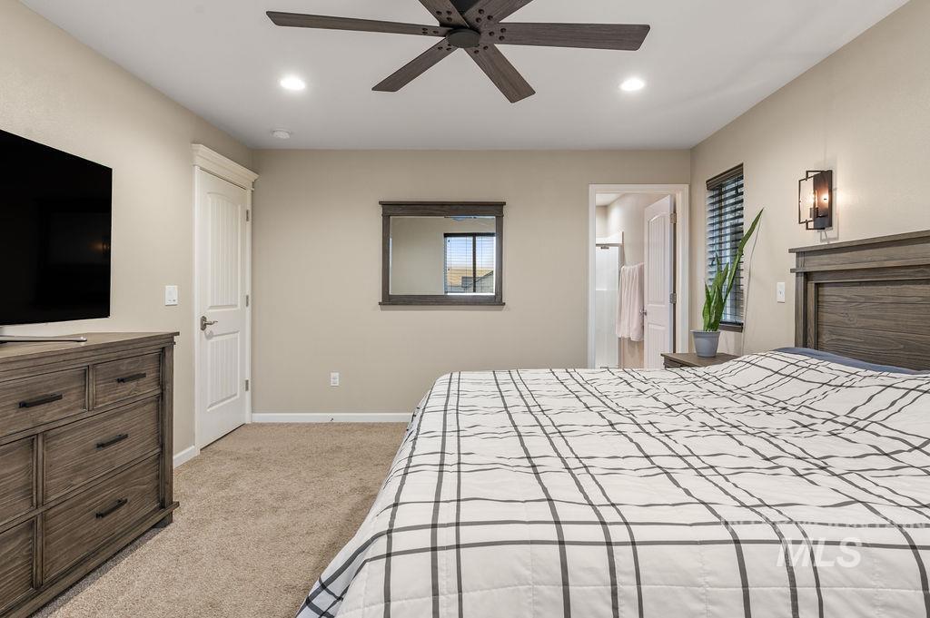 Bedroom with a grid-pattern quilt, matching wood furniture, and an open doorway to the bathroom.