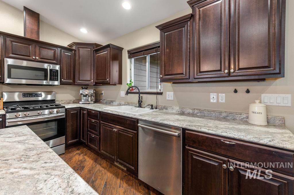 Kitchen with dark cherry cabinets, granite counters, stainless steel appliances, and hardwood flooring.