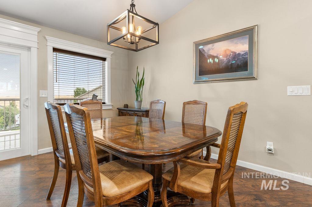 Furnished dining room with a polished wood table, woven-back chairs, and a geometric pendant light.