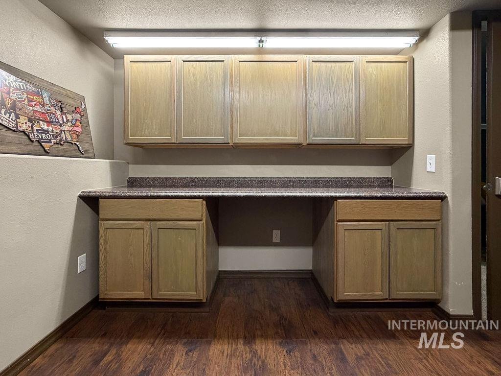 Built-in workspace with light wood cabinets, dark countertop, and open knee space.