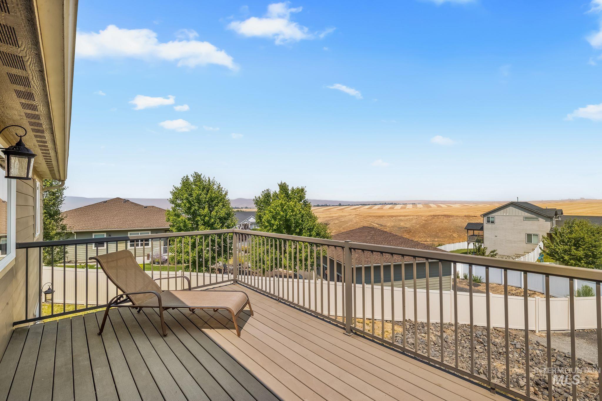 Elevated deck with a lounge chair overlooking neighboring homes and golden fields.