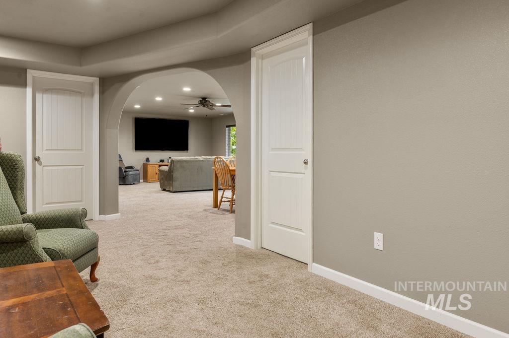 Carpeted room with an arched opening to a living area and white paneled doors.