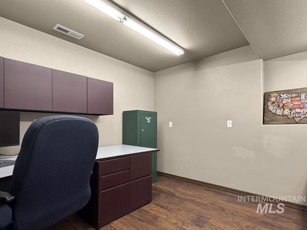 Office with burgundy cabinets, a desk, green storage safe, and wood-look flooring.