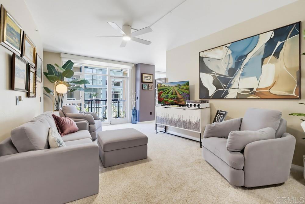 Furnished living room with two sofas, large abstract wall art, and glass doors to a balcony.