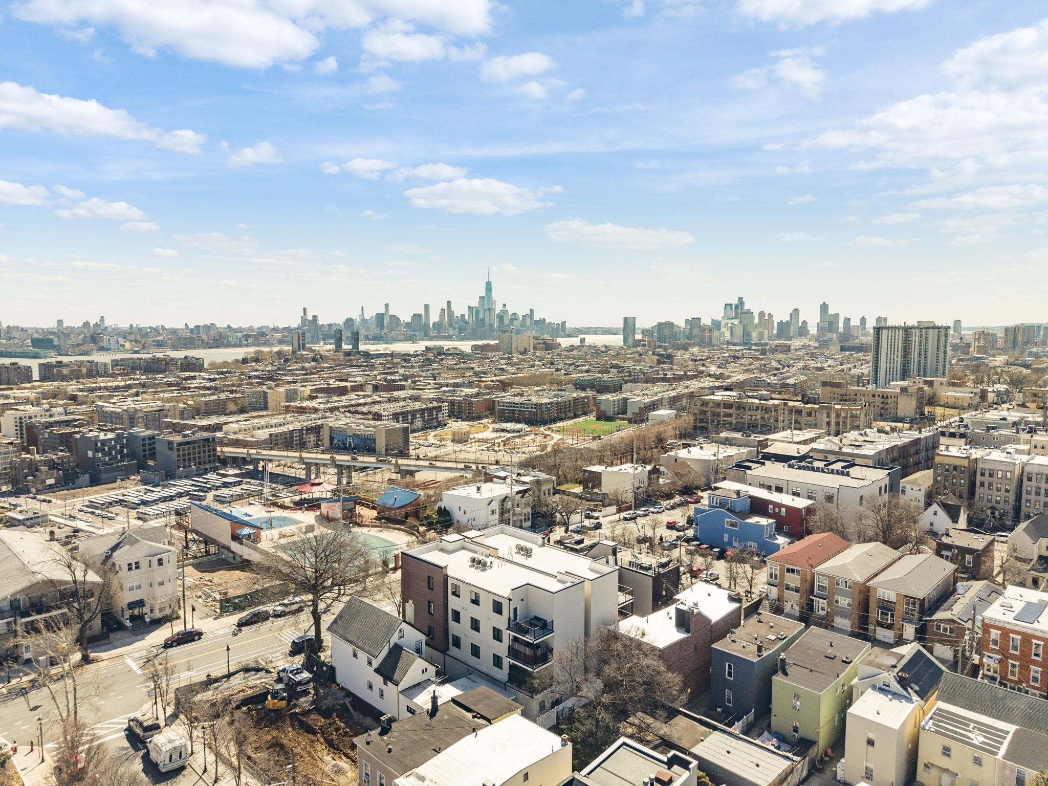 Aerial view over Union City rooftops toward the Manhattan skyline.