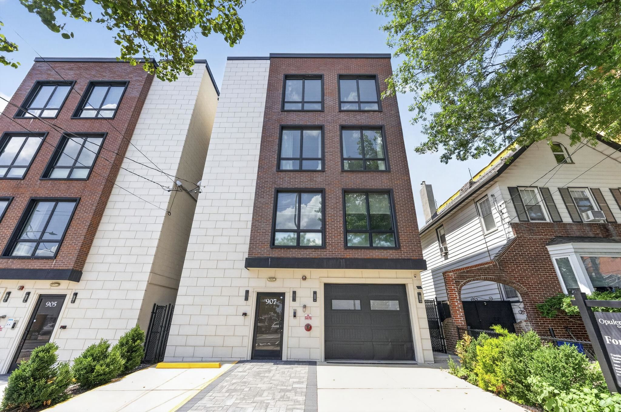Modern brick residence with pale stone cladding, black-framed windows, and a street-level garage.