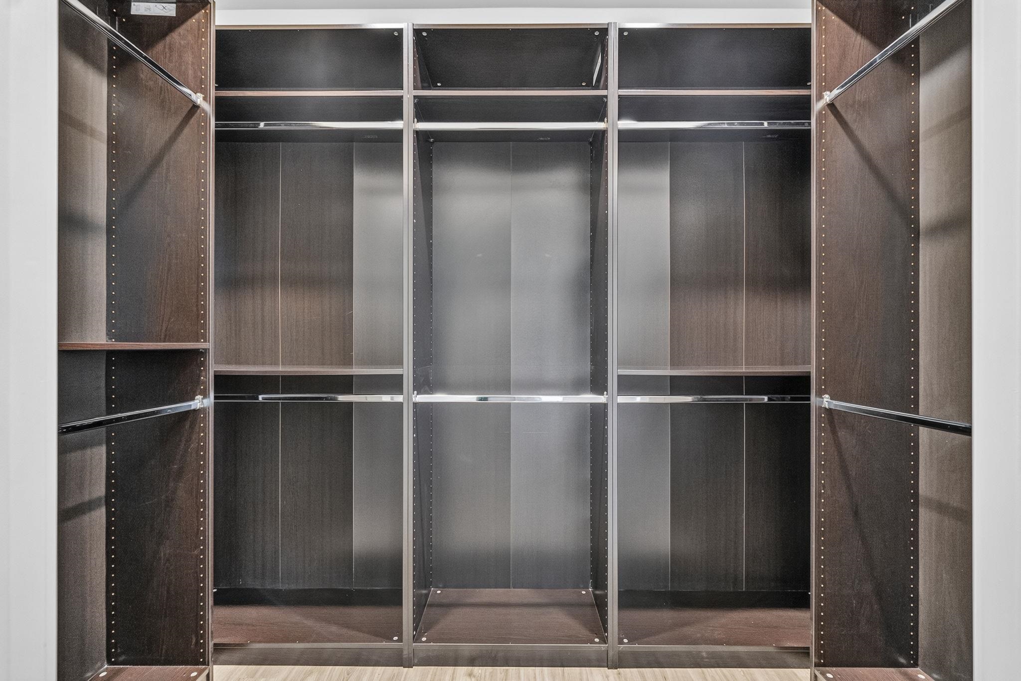 Built-in walk-in closet with dark wood cabinetry, open shelves, and hanging rails.