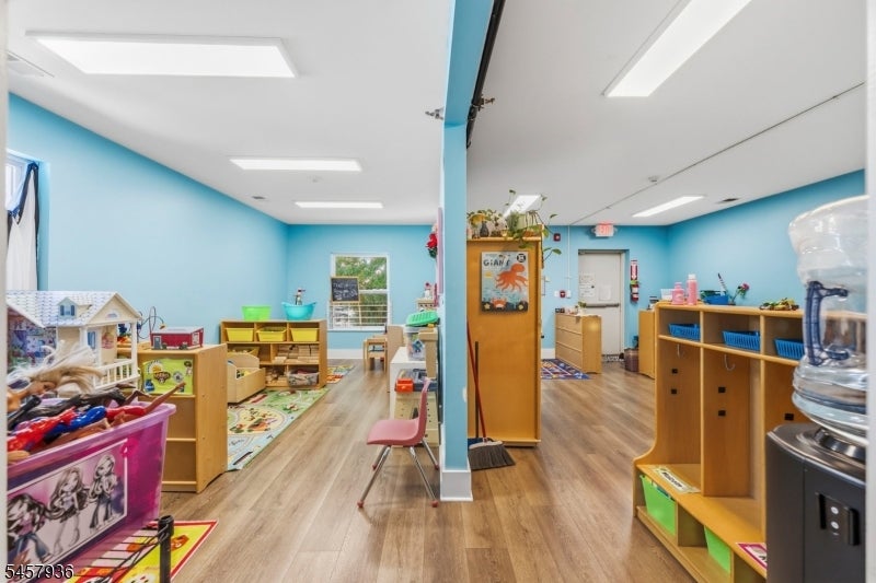 Childcare classroom with blue walls, low wooden shelves, toys, and colorful play mats.