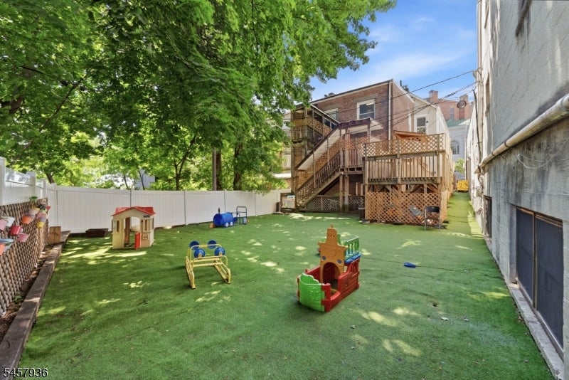 Backyard with artificial turf, children's play equipment, and a raised wooden deck.