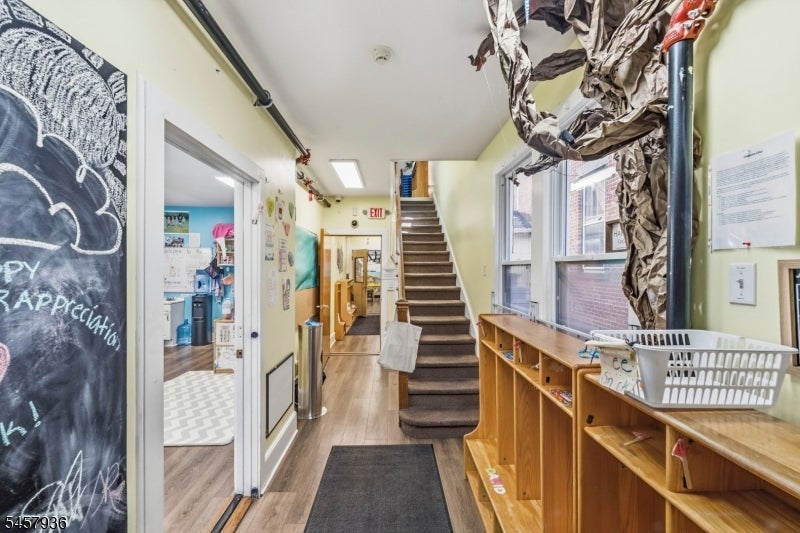 Entry hallway with central staircase, built-in wooden cubbies, and large windows.