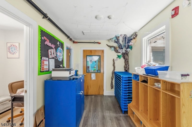 Interior hallway with blue storage trays, wooden cubbies, and a colorful bulletin board.