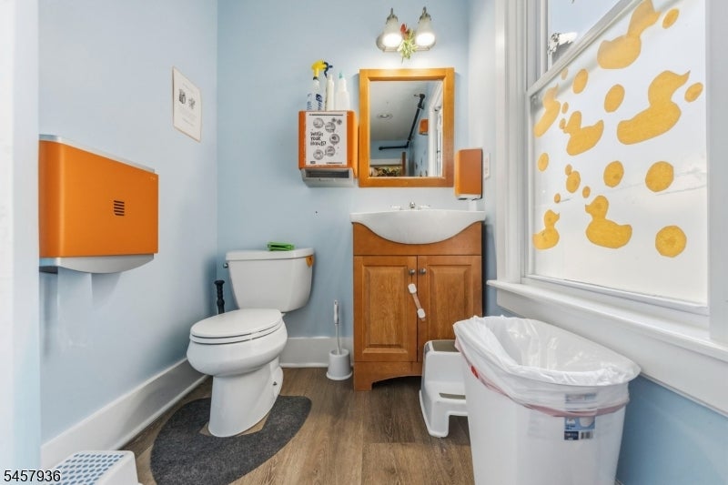 Bathroom with a wooden vanity, white toilet, and window covered in yellow duck shapes.