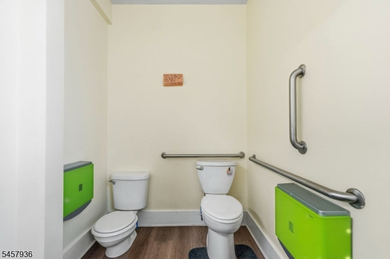 Restroom with two toilets, metal grab bars, and bright green wall-mounted fixtures.