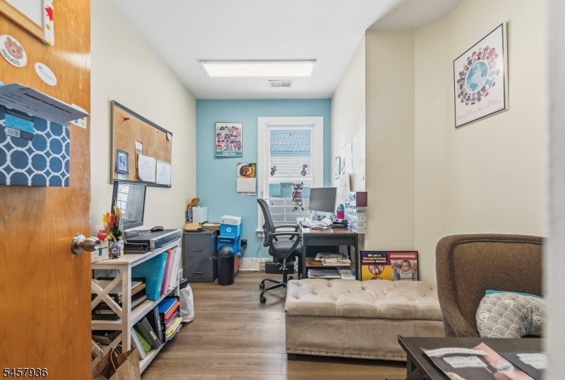 Furnished home office with a desk, turquoise accent wall, and seating area.