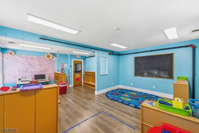 Playroom with blue walls, a large chalkboard, colorful rugs, and child-sized furniture.