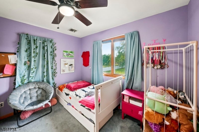 Child's bedroom with lavender walls, a white bed and crib, teal curtains, and medals above the crib.