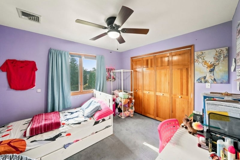 Bedroom with lavender walls, wooden closet doors, a white bed, and a window with blue curtains.