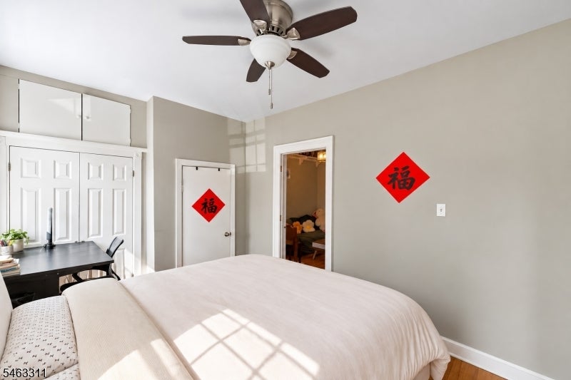 Bedroom with a large bed, ceiling fan, white closet doors, and red 福 decorations.