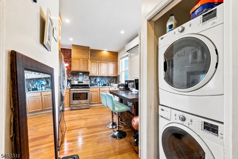 Kitchen with light wood cabinets and an island, seen beside a stacked washer and dryer.