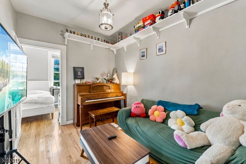 Living room with a green sofa, plush cushions, upright piano, and high wall shelves.