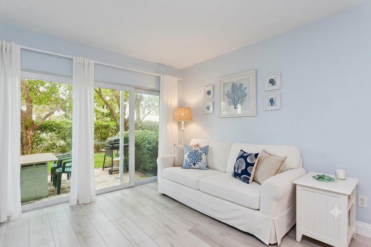 Living room with a white sofa and sliding glass doors overlooking a garden patio.